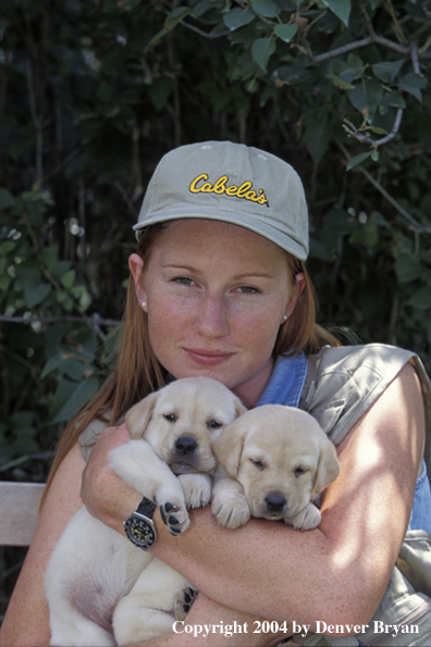 Woman with yellow Labrador Retriever puppies