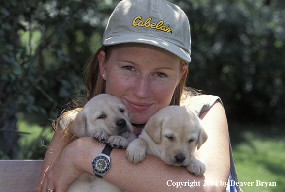 Woman with yellow Labrador Retriever puppies