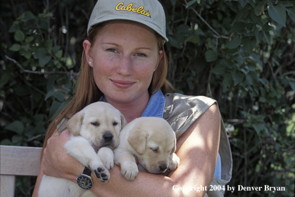 Woman with yellow Labrador Retriever puppies