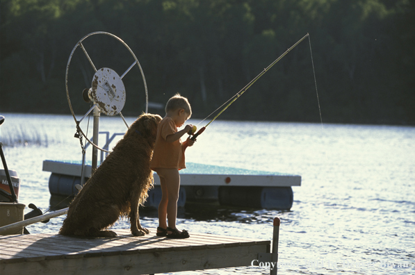 Boy spincast fishing with Golden Retriever