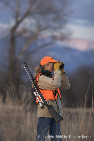 Woman big game hunter glassing for game.
