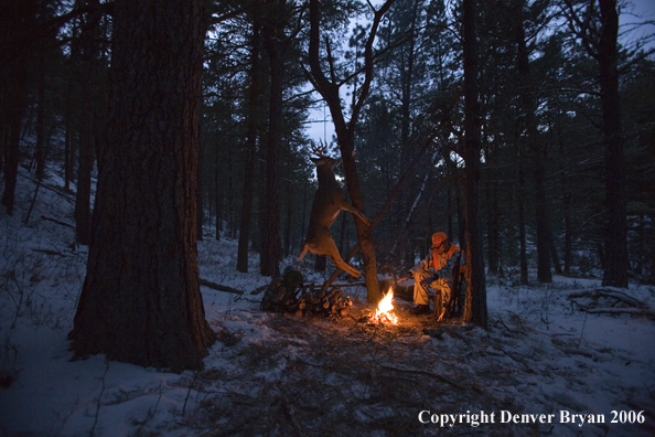 Deer hunter with bagged deer in camp in winter.  