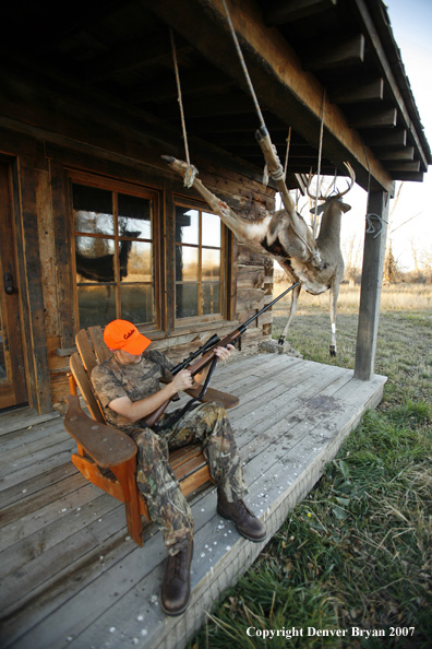 Hunter on porch of cabin check rifle