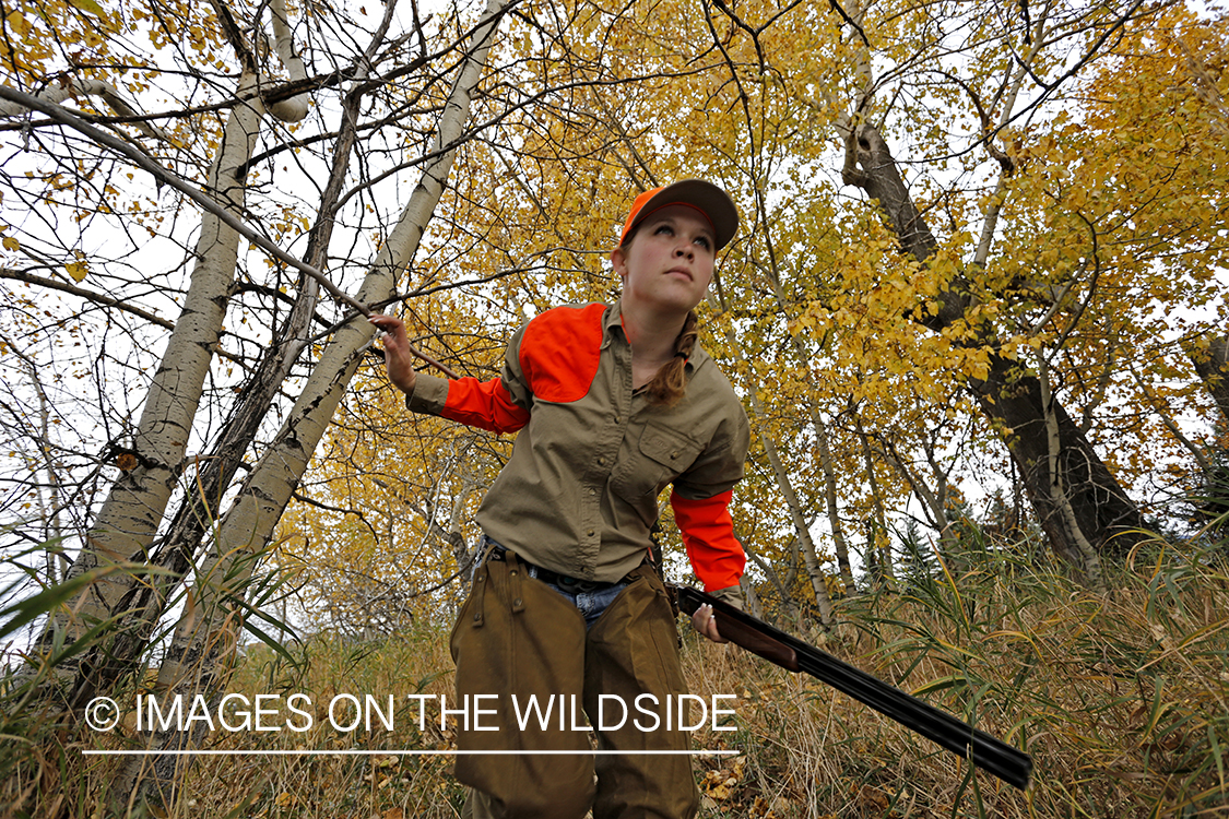 Woman in woodland hunting pheasant.