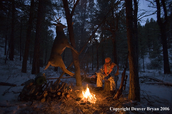 Deer hunter with bagged deer in camp in winter.  