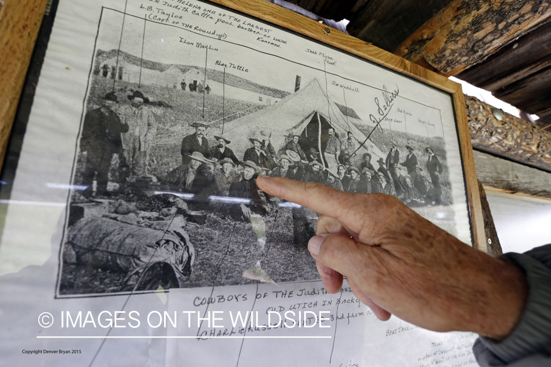Dusty Don Waite pointing to old photo of Charlie Russell in Utica, Montana.