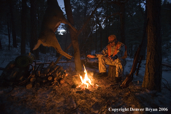 Deer hunter with bagged deer in camp in winter.  