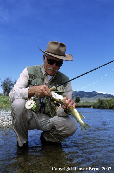 Flyfisherman taking fly out of fish's mouth
