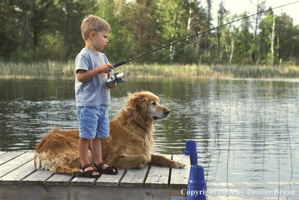 Boy spincast fishing with Golden Retriever
