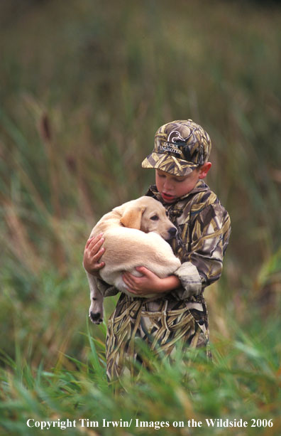 Young boy and yellow labrador retriever puppy.