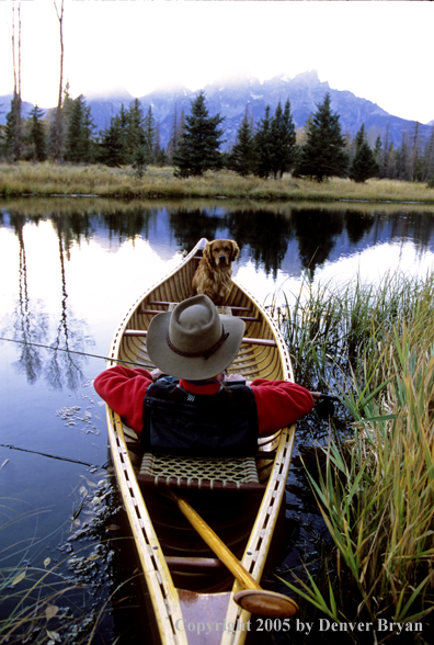 Flyfisherman with Golden Retriever in wooden cedar canoe.  