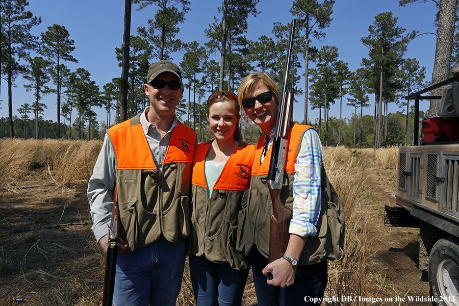 Adults with young hunter in field. 