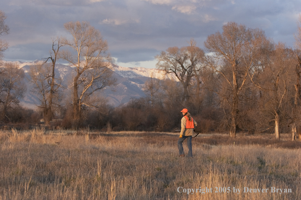 Woman big game hunter walking in field.