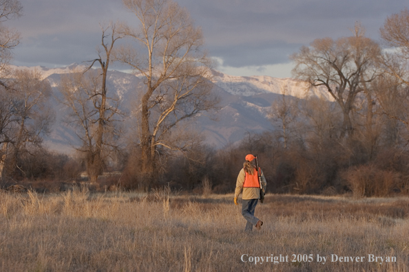 Woman big game hunter walking in field.