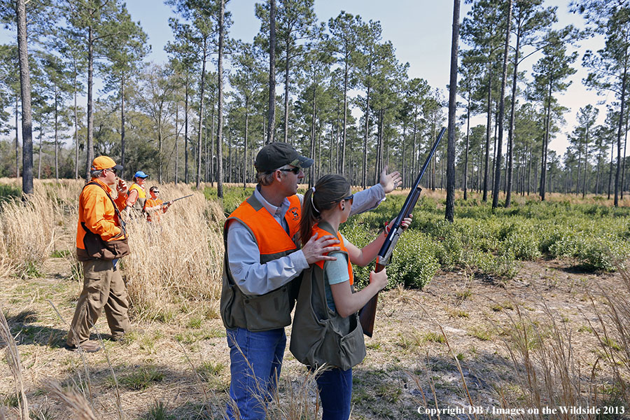 Adults with young hunters in field. 