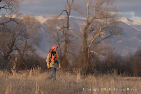 Woman big game hunter walking in field.
