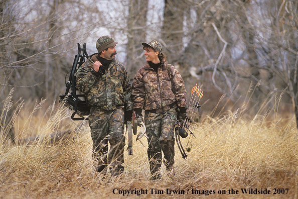 Bowhunters walking across field.
