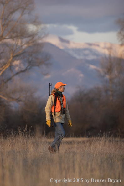 Woman big game hunter walking in field.