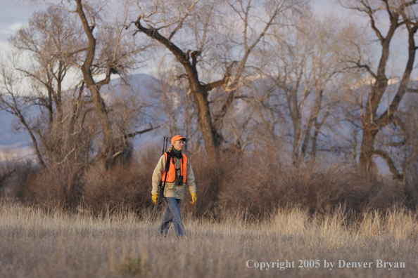 Woman big game hunter walking in field.