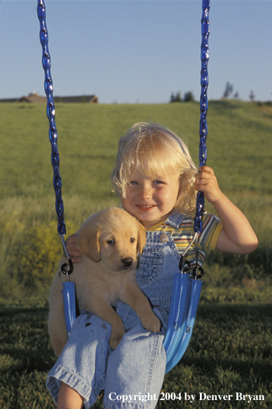 Child with yellow Labrador Retriever puppy
