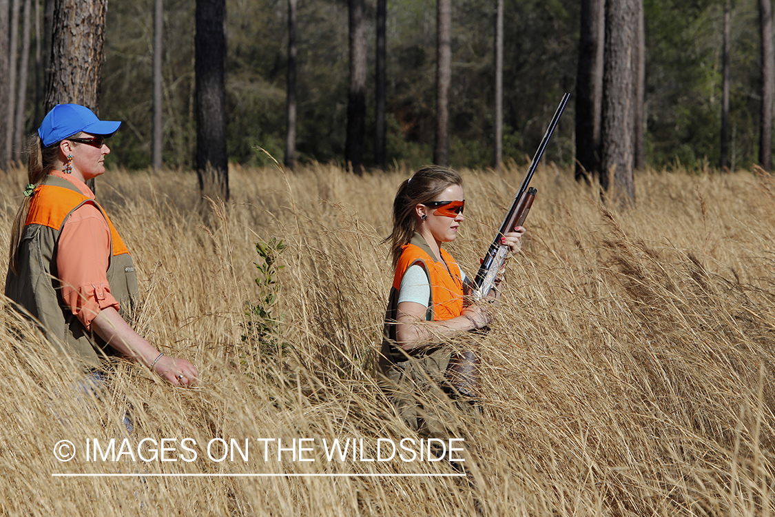 Adult with young hunter in field.
