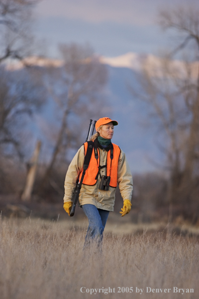 Woman big game hunter walking in field.