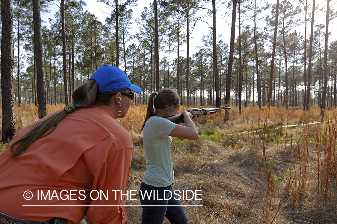 Adult with young hunter in field.
