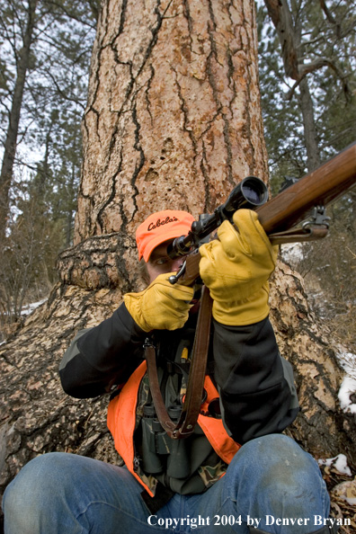 Big game hunter aiming/shooting at game.