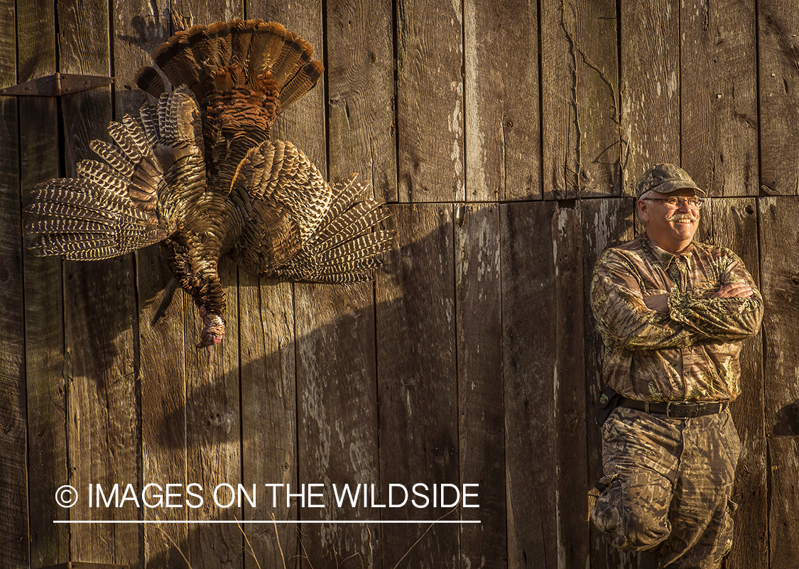 Turkey hunter with bagged gobbler in field.
