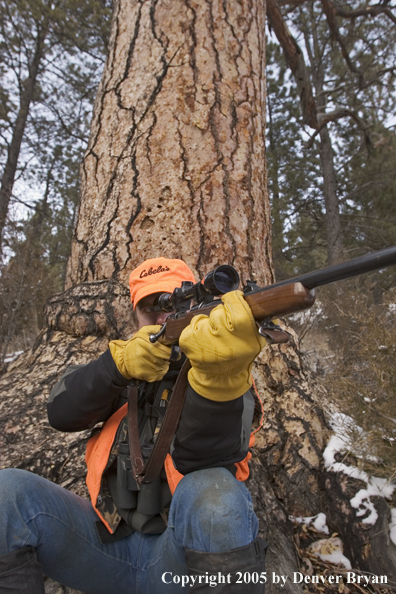 Big game hunter aiming/firing at game.