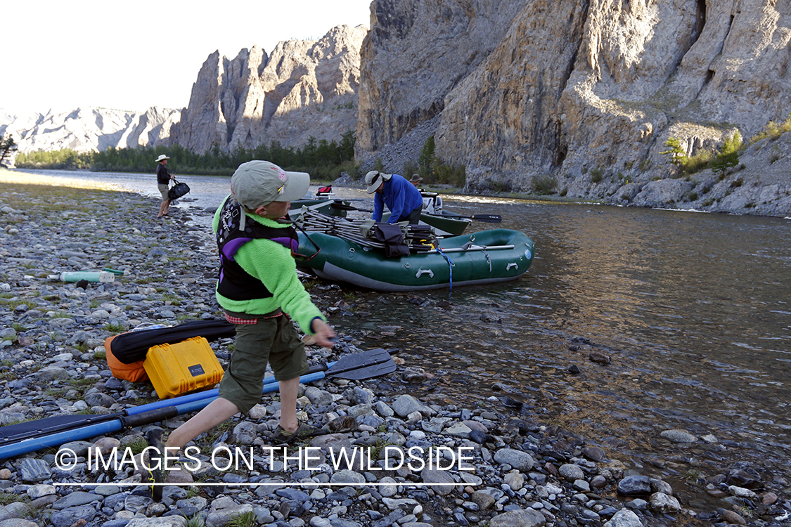 Young boy skipping rocks on the river.