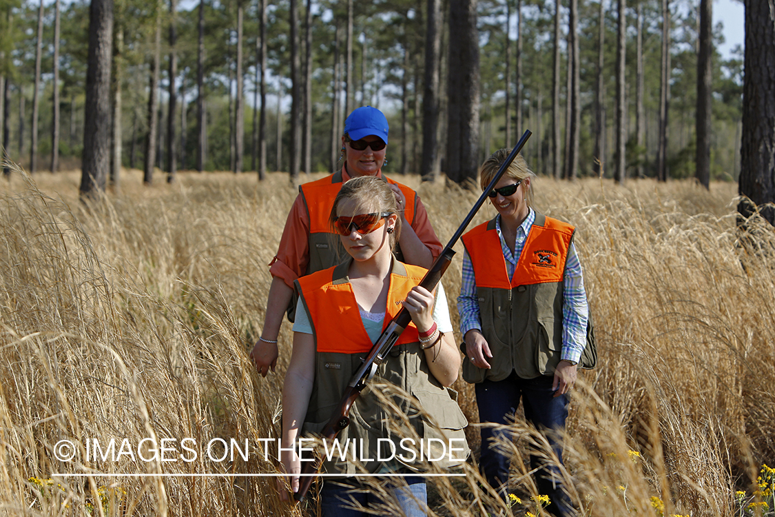 Adults with young hunter in field.
