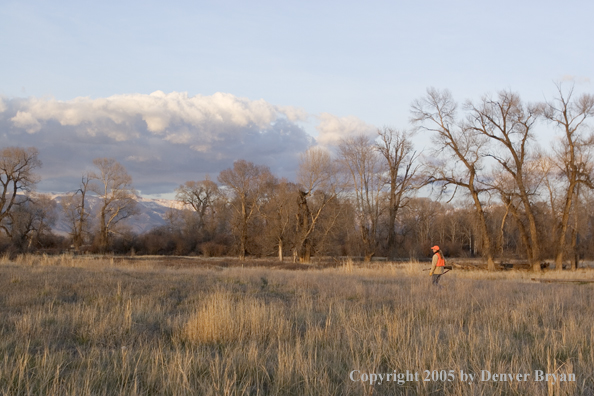 Woman big game hunter walking in field.