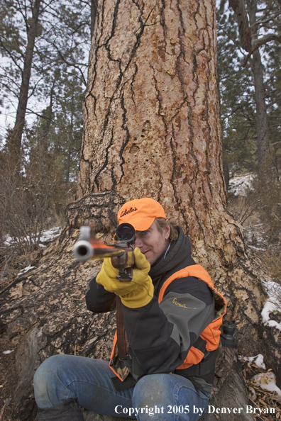 Big game hunter aiming/firing at game.