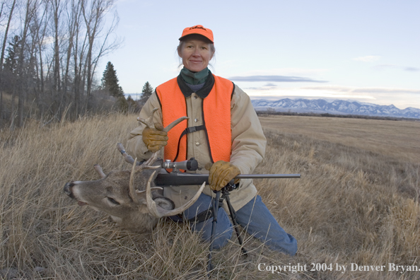 Woman big game hunter with bagged white-tailed deer buck.