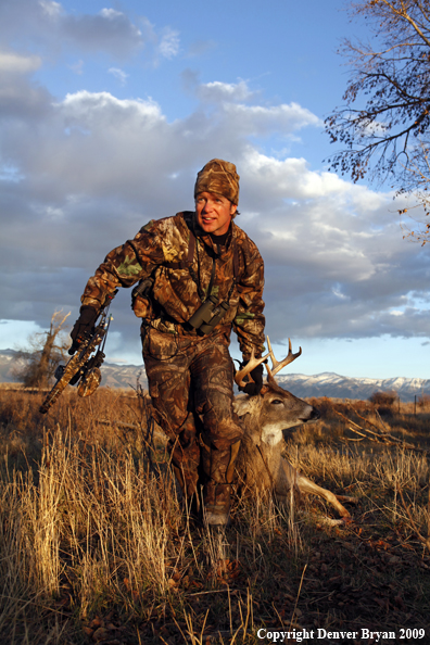 Bowhunter dragging bagged whitetail deer.