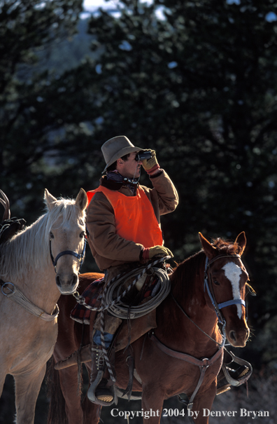 Successful big game hunter glassing from horseback.