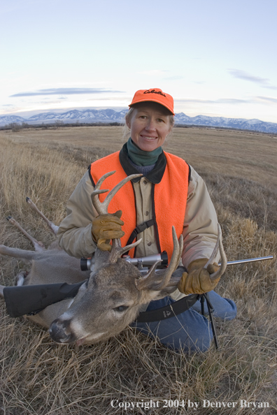 Woman big game hunter with bagged white-tailed deer buck.