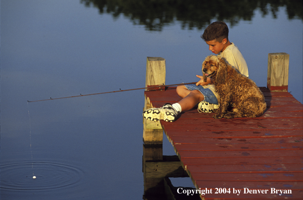 Boy spincast fishing with dog.
