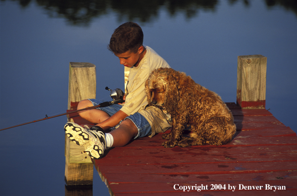 Boy spincast fishing with dog.