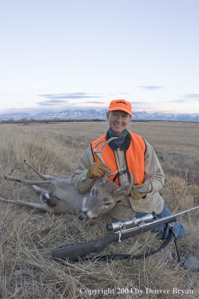 Woman big game hunter with bagged white-tailed deer buck.