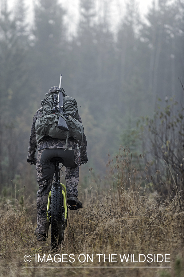 Hunter riding mountain bike through trail.