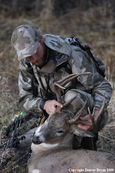 Bowhunter with bagged whitetail buck.