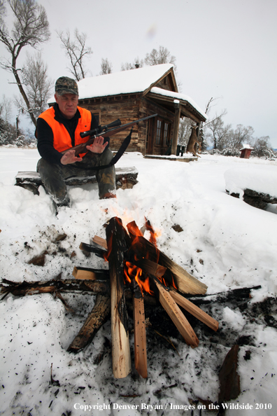White-tailed deer hunter harming hands by campfire