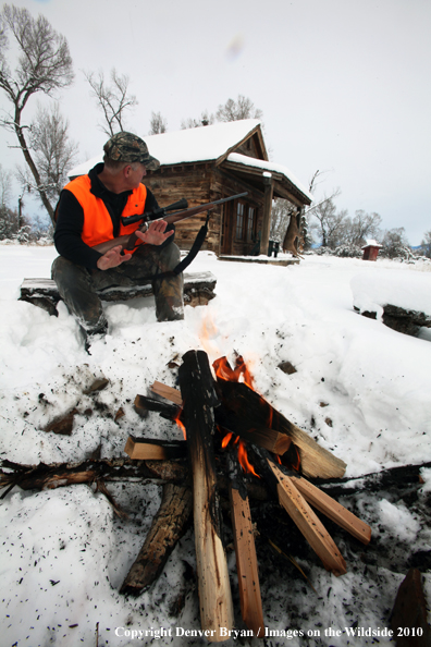 White-tailed deer hunter harming hands by campfire