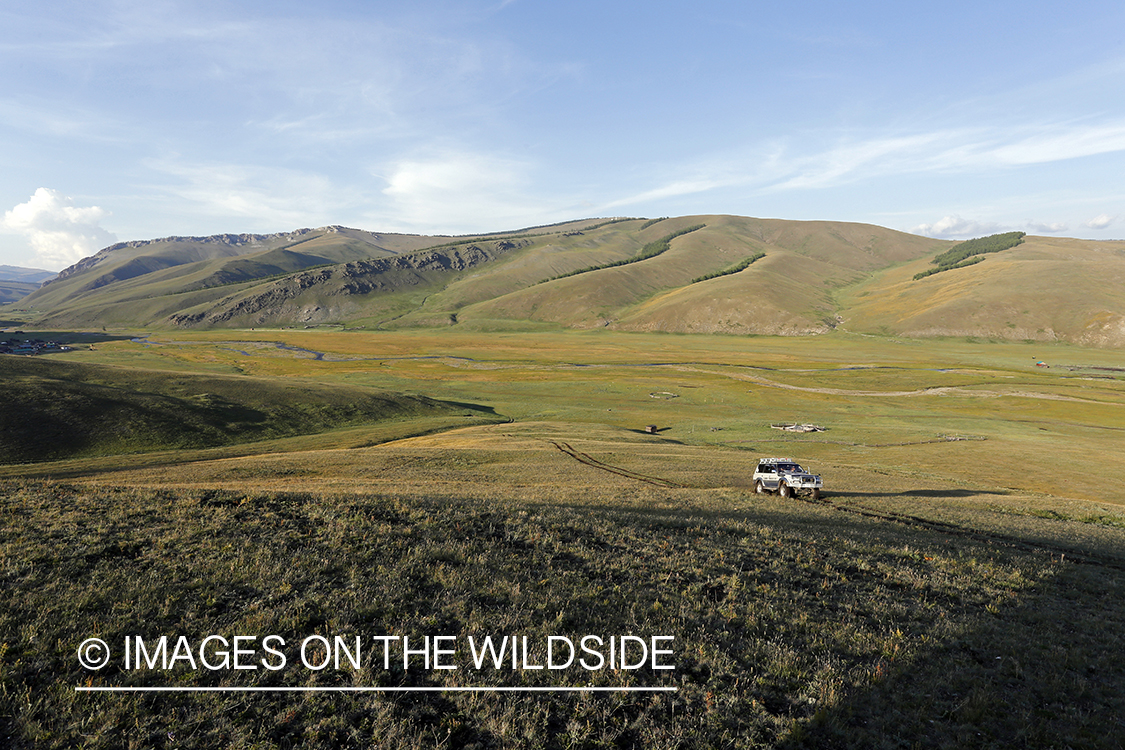 Land Rover driving through mongolian steppe to river camp.