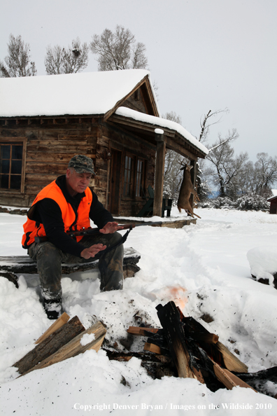 White-tailed deer hunter harming hands by campfire