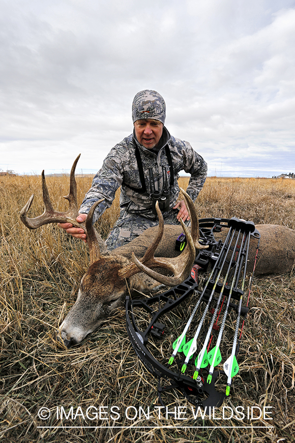 Bowhunter with downed white-tailed buck.