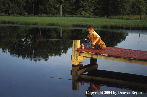 Boy spincast fishing with dog.