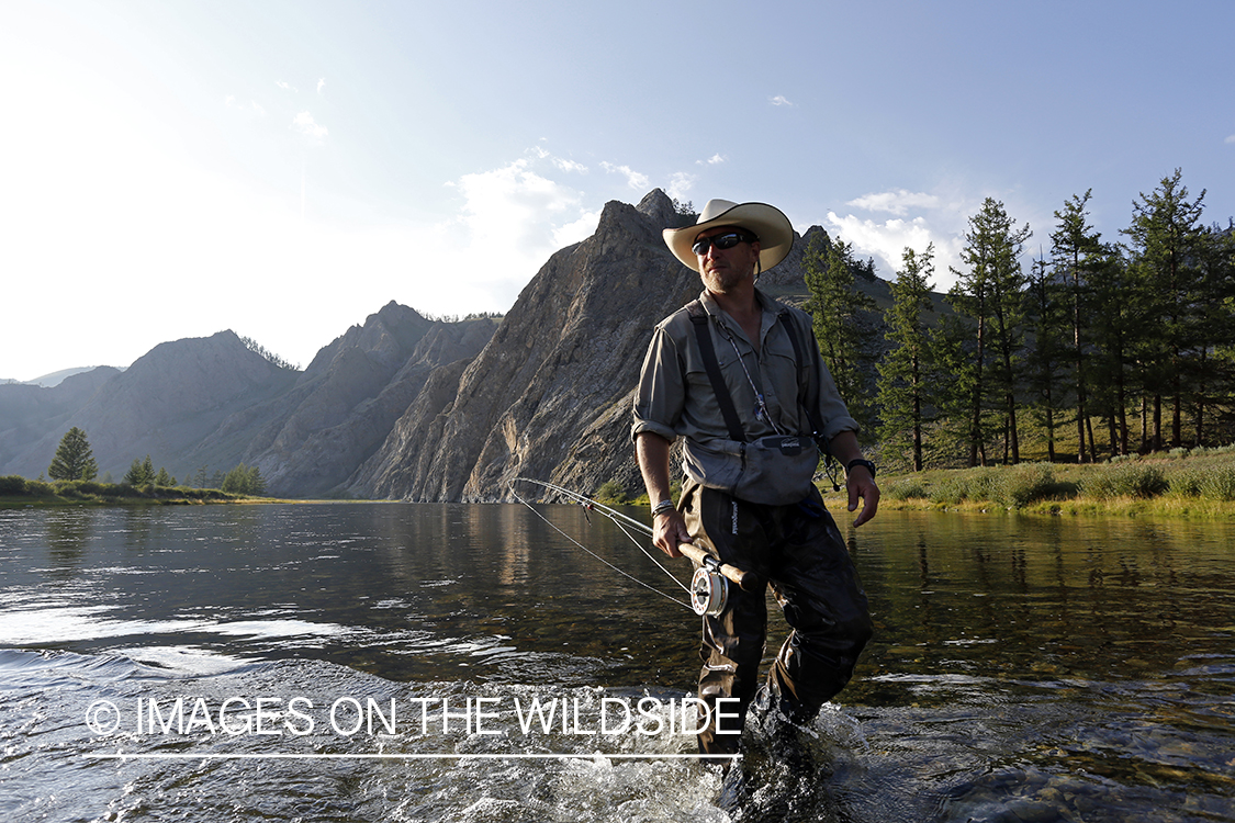 Flyfisherman wading through Delger River, Mongolia.